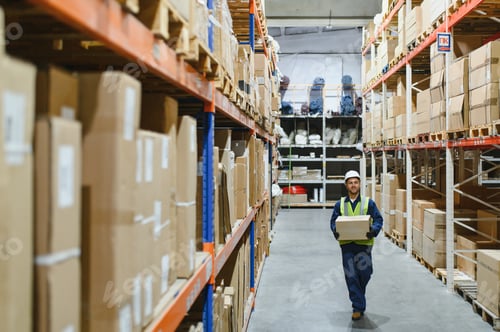 Preview: Warehouse worker in blue uniform holding a large cardboard box. Stacks of boxes are visible in the b