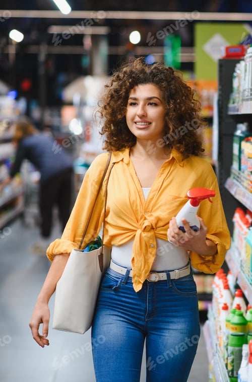 Preview: Woman smiling buying cleaning supplies in supermarket aisle