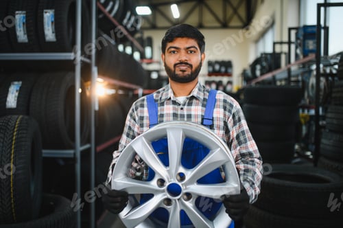 Preview: Mechanic holding alloy wheel in tire shop