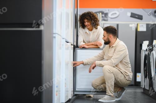 Preview: Couple choosing refrigerator in electronics store examining home appliances