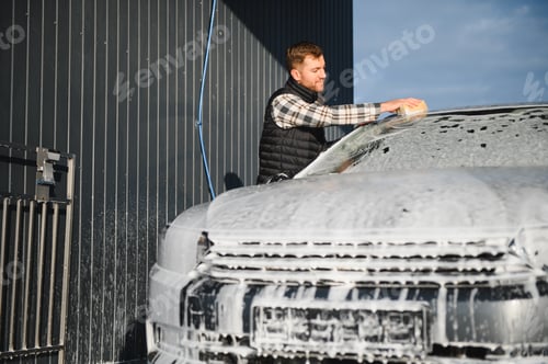 Preview: Man worker with a sponge washes a car with foam. Car wash and car care