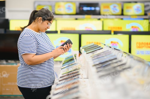 Preview: Indian woman choosing a new mobile phone in a shop