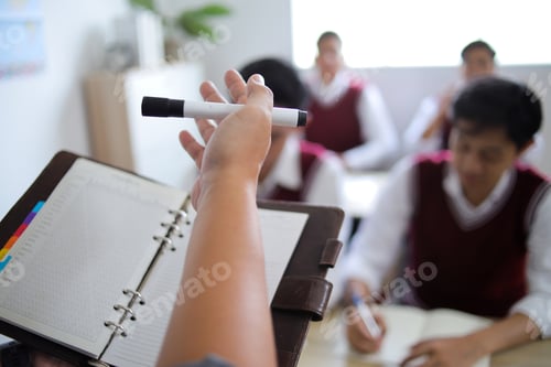 Preview: Teacher Hand Pointing with Marker and Holding Notebook Planner While Explaining Lesson to Student