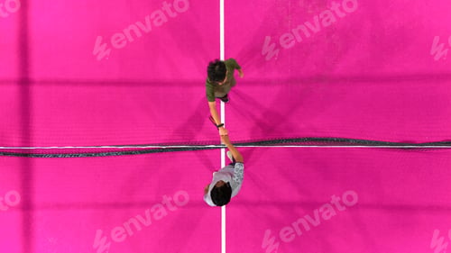 Preview: Top Down Drone View of Two Player Doing Fist Bump Over Net on Vibrant Pink Padel Court