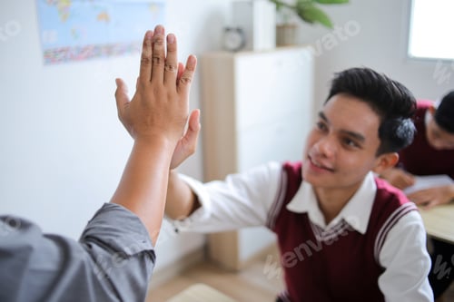 Preview: Closeup of High School Student Giving High Five to His Teacher in Classroom