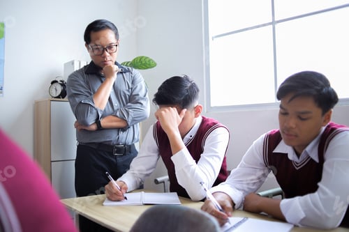 Preview: Asian Teacher Standing Thoughtfully Next to High School Student Who Look Stressed and Anxious