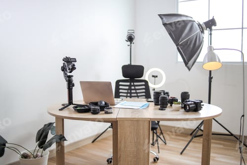 Preview: Photographer Workspace with Camera Equipment, Lenses, Laptop, and Studio Lighting Setup on Table