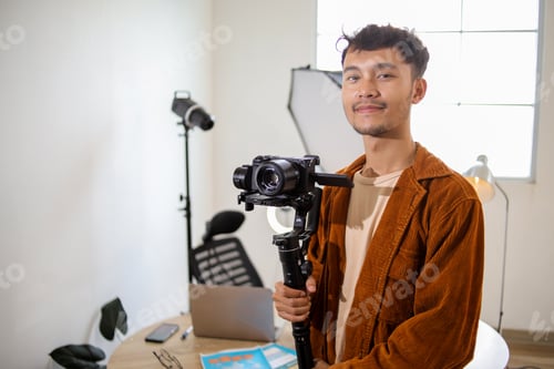 Preview: Portrait of Smiling Young Male Videographer Holding Mirrorless Camera on Gimbal Stabilizer