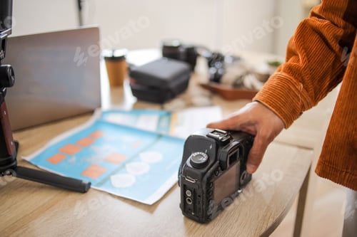 Preview: Closeup Photographer Hands Grabbing Digital DSLR Camera From Messy Studio Desk Workspace