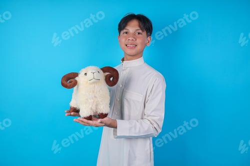 Preview: Smiling Asian Muslim Boy Holding Sheep Doll In Palms For Eid Al Adha Concept