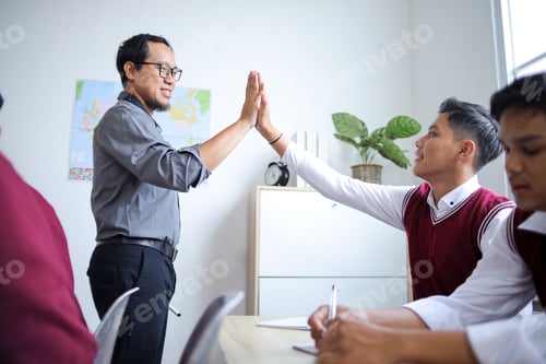 Preview: Male Asian Teacher Giving High Five to His School Student During Cheerful Classroom Session
