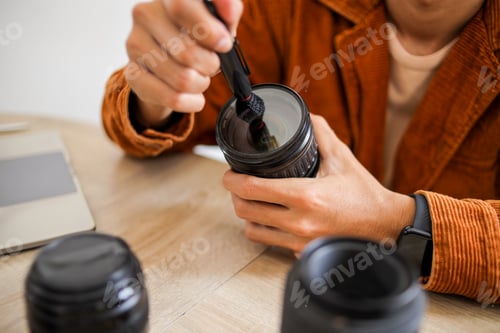 Preview: Close up of Photographer Cleaning Camera Lens with Specialized Brush Pen Tools