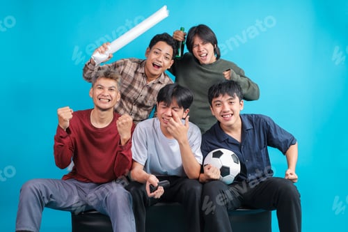 Preview: Group of Excited Asian Football Fans Celebrating Goal While Sitting on Couch