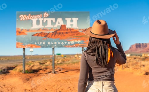 Preview: Woman wearing cowboy hat looking at utah welcome sign