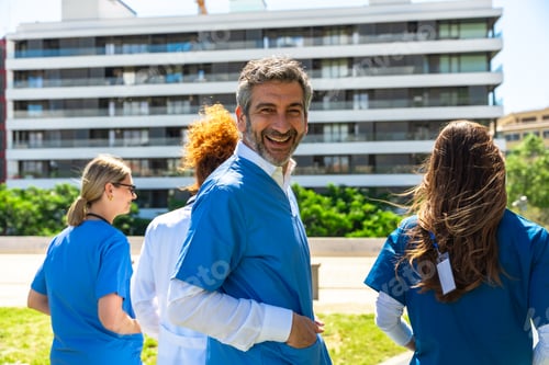 Preview: Happy healthcare professionals walking outdoors near hospital