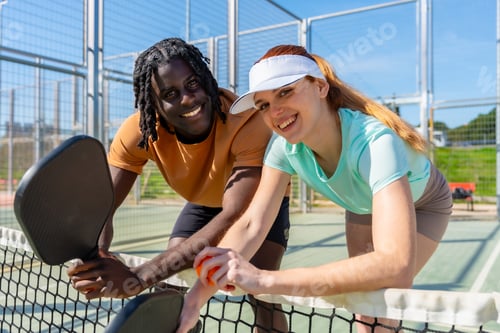 Preview: Diverse couple playing pickleball on outdoor court enjoying active lifestyle