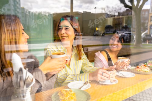 Preview: Three smiling women friends enjoying coffee breakfast at cafe