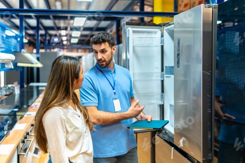 Preview: Store sales assistant explaining refrigerator features to customer