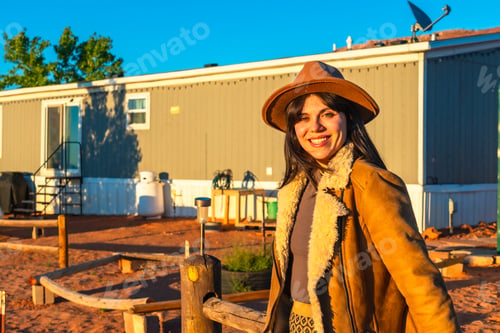 Preview: Young woman smiling in cowboy hat at sunset with mobile home