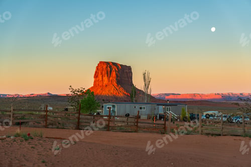Preview: Monument valley butte at sunrise with moon and desert home