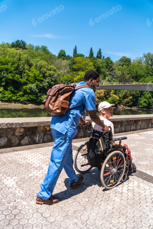Preview: Caregiver pushing elderly man in wheelchair outdoors
