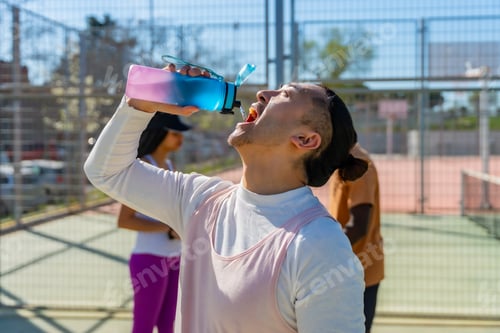 Preview: Man drinking water on pickleball court for hydration