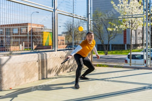 Preview: Young man playing pickleball on outdoor court