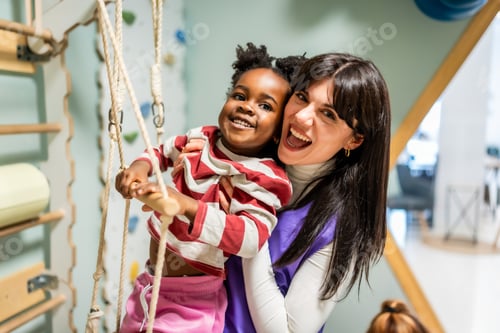 Preview: Happy teacher supporting african american child playing on ropes
