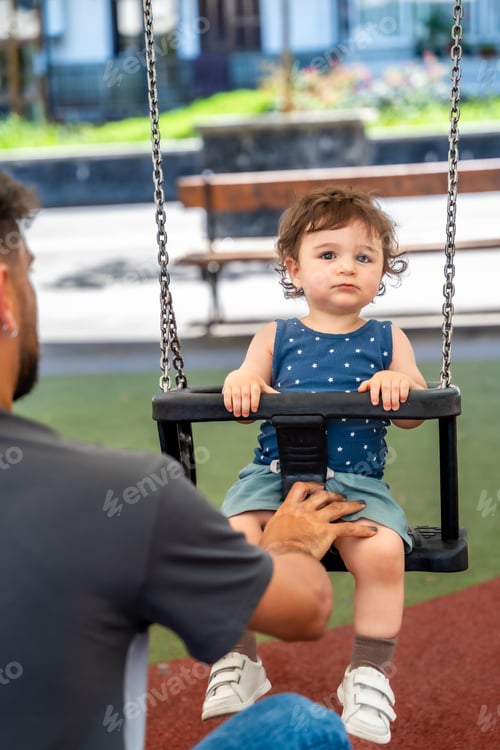 Preview: Father playing with son on playground swing
