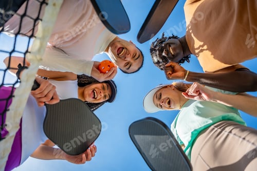 Preview: Diverse friends laughing huddle under pickleball net