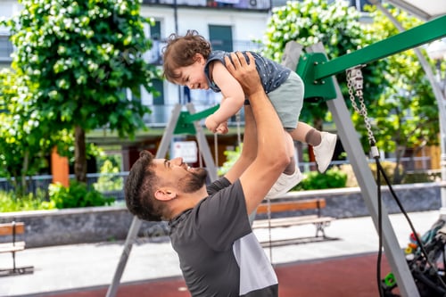 Preview: Father playing with son, lifting baby in park
