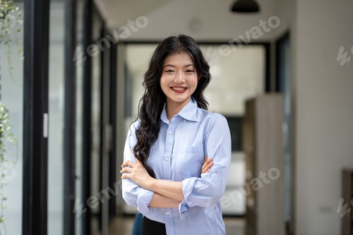 Preview: Confident young woman standing in modern office space with smile