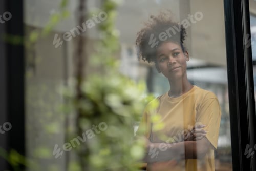 Preview: Thoughtful Woman with Natural Hair Looking Through a Window