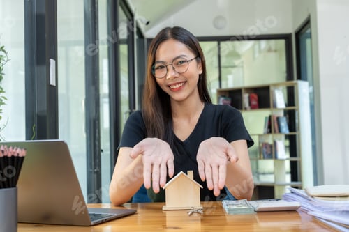 Preview: Woman with Model House and Laptop at Modern Office Table