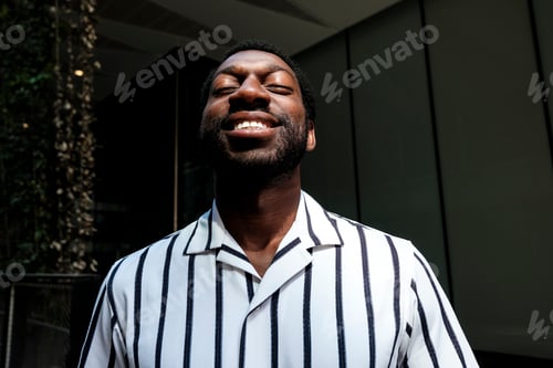 Preview: Happy black man enjoying sunlight with closed eyes