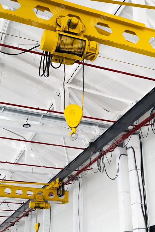 Preview: Yellow overhead crane with hook in a bright industrial hall. Steel beams and clean factory interior