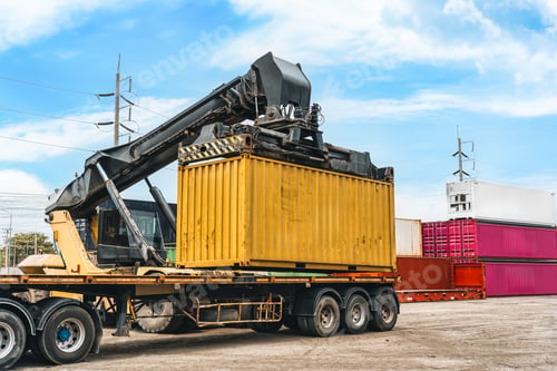 Preview: Reach stacker loading yellow shipping container onto truck at industrial terminal port