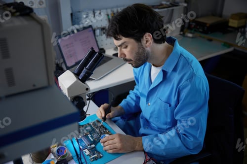Preview: A technician repairs a circuit board with a microscope in a high-tech setting