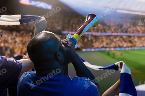 Preview: Back view close up of football fan with blue jersey blowing vuvuzela