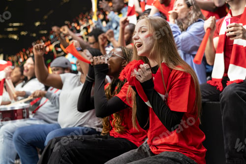 Preview: Young female football supporter holding red scarf near her mouth