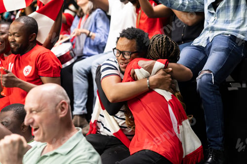 Preview: Happy soccer fans celebrating football match victory and embracing each other