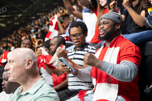 Preview: Excited black soccer fans with gambling app open checking high risk bet ticket