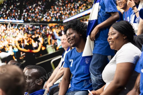 Preview: Diverse blue team football supporters chanting in packed stadium stands
