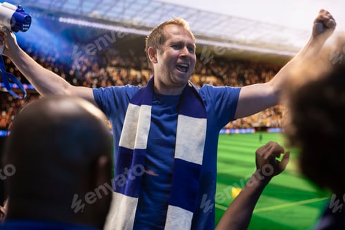 Preview: Football supporters shouting with raised arms in sports arena
