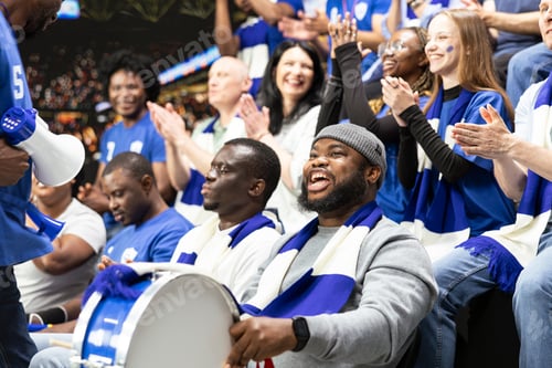 Preview: Energetic football supporter beating percussion drum in blue fan section