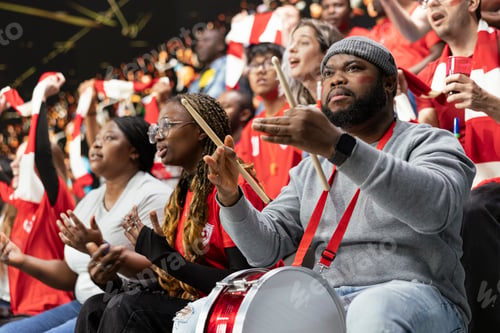 Preview: Frustrated football supporter with drum reacting with open hands in red stadium