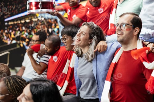 Preview: Football supporters embracing and singing together in stadium stands