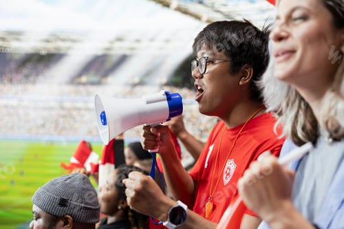 Preview: Young football supporter leading stadium chants with a megaphone