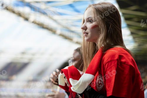 Preview: Young female football supporter in red shirt watching intense final minutes