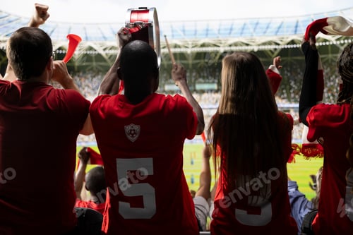 Preview: Back view of soccer supporters in red jerseys watching field from stadium stands